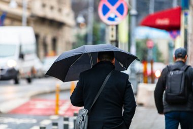 Romanya 'nın Bükreş kentinde 2021' de yağmurlu bir günde sokakta şemsiyesi olan insanlar