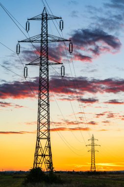 Gün batımında elektrik kablolarıyla elektrik direğinin ayrıntıları