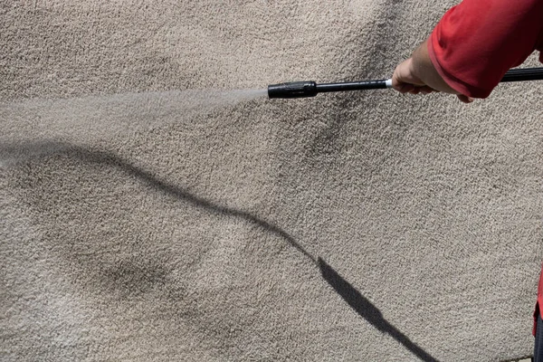 Washing carpets with high pressure washer. Cleaning the carpet with a gun for washing high pressure water