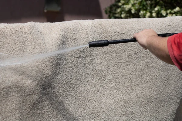 Yüksek basınçlı yıkamalı halılar. Yüksek basınçlı suyu yıkamak için halıyı silahla temizlemek.