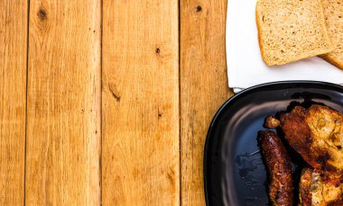 Baharatlı domuz pirzolası ve siyah bir tabakta tütsülenmiş sosis, ahşap masa üzerinde, bbq için et, üst manzara, fotokopi alanı, barbekü konsepti