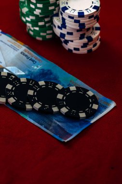 Kırmızı arka planda parası olan poker çipleri yığını, CHF para birimi