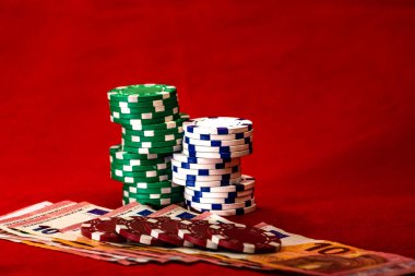 Kırmızı arkaplanda parası olan poker çipleri yığını, EURO para birimi