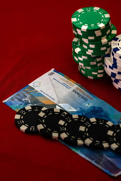 Stacks of poker chips with money on red background, CHF currency