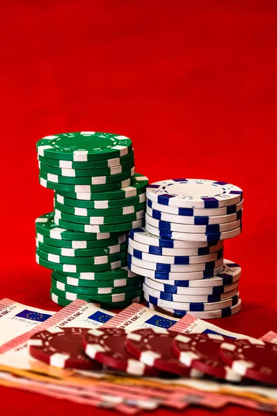 Stacks of poker chips with money on red background, EURO currency