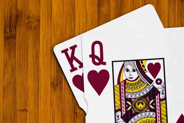 Playing cards king and queen cards close up, isolated on wooden table. Casino concept, risk, chance, good luck or gambling.