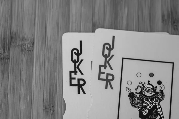 Playing cards joker card close up, isolated on wooden table. Casino concept, risk, chance, good luck or gambling.