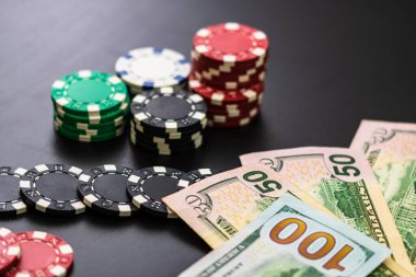 Siyah arka planda yığınla poker fişi ve dolar banknotları. Poker konsepti, çip ve para.