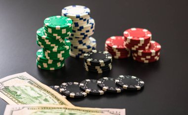 Siyah arka planda yığınla poker fişi ve dolar banknotları. Poker konsepti, çip ve para.