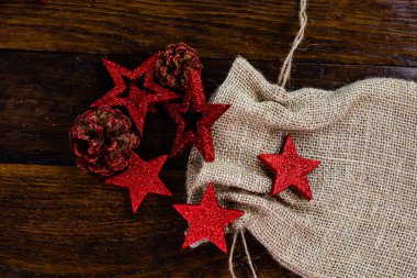Noel çuvalı, parıltılı ve parlak Noel süslemeleri. Tahta üzerinde Noel süslemeleri. Kırmızı Noel yıldızları ve kar taneleri.