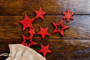 Noel çuvalı, parıltılı ve parlak Noel süslemeleri. Tahta üzerinde Noel süslemeleri. Kırmızı Noel yıldızları ve kar taneleri.
