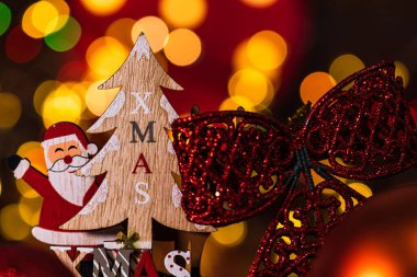 Arka planda bulanıklık ve odak ışıkları karşısında Noel süslemeleri. Noel Baba, ren geyiği, Noel ağacı ve ışıltılı Noel toplarıyla ahşap bir Noel kızağı çek.
