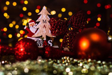Arka planda bulanıklık ve odak ışıkları karşısında Noel süslemeleri. Noel Baba, ren geyiği, Noel ağacı ve ışıltılı Noel toplarıyla ahşap bir Noel kızağı çek.