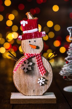 Arka planda bulanıklık ve odak ışıkları karşısında Noel süslemeleri. Dekoratif ahşap kardan adam ve ışıltılı Noel topları