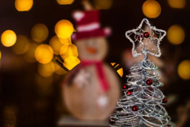 Arka planda bulanık bir Noel süsü var. Küçük gümüş telli Noel ağacı. Mini Noel ağacı.