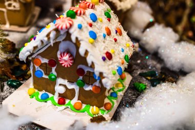 Renkli zencefilli kurabiye evi, bulanık arka planda, Noel süslemesiyle izole edilmiş..