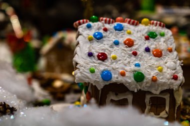 Renkli zencefilli kurabiye evi, bulanık arka planda, Noel süslemesiyle izole edilmiş..