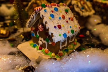 Renkli zencefilli kurabiye evi, bulanık arka planda, Noel süslemesiyle izole edilmiş..