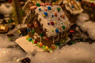 Arka planda bulanık bir Noel süsü var. Şekerli zencefilli ev. Zencefilli evin çatısı renkli şekerlerle dolu..
