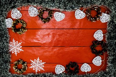 Noel çelengi ve süslemeleri olan kırmızı tahta üzerinde Noel kompozisyonu. Sınır ve kopyalama alanı ile yaratıcı kompozisyon, üst görünüm, düz yatay. Noel çerçevesi.