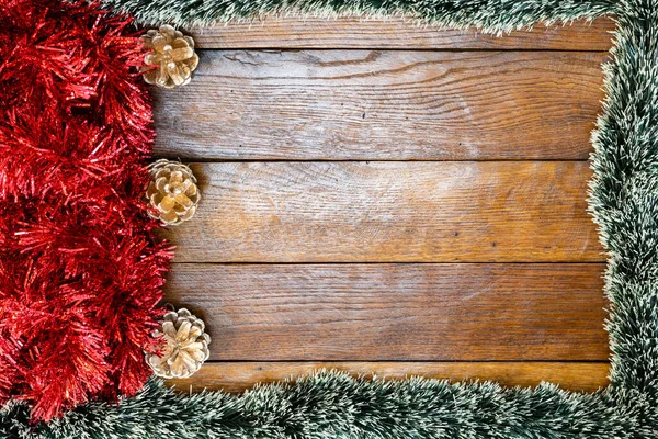 Christmas composition on wooden board with Christmas garland and decorations. Creative composition with border and copy space, top view, flat lay. Christmas frame.