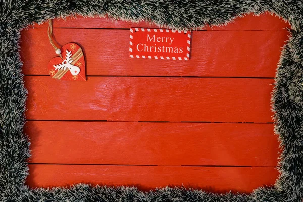 Noel çelengi ve süslemeleri olan kırmızı tahta üzerinde Noel kompozisyonu. Sınır ve kopyalama alanı ile yaratıcı kompozisyon, üst görünüm, düz yatay. Noel çerçevesi.