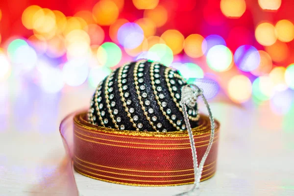カラフルなガーランドに囲まれた黒と光沢のあるクリスマスボール ぼやけたライトの背景にクリスマスの組成 — ストック写真