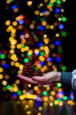 Kadın eli Noel süslemesi tutuyor. Noel ve Yeni Yıl tatilleri arka plan, Noel süsleri ve bulanık ışıklarla kış sezonu