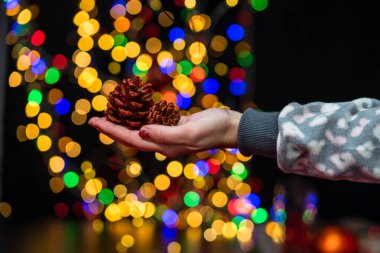 Kadın eli Noel süslemesi tutuyor. Noel ve Yeni Yıl tatilleri arka plan, Noel süsleri ve bulanık ışıklarla kış sezonu