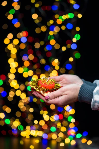 Woman\'s hands hold christmas decoration. Christmas and New Year holidays background, winter season with Christmas ornaments and blurred lights