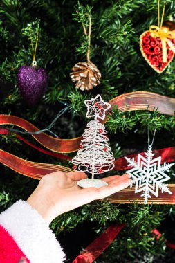 Hsnd Noel ağacının önünde küçük bir Noel ağacı heykeli tutuyor..