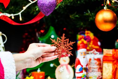 Noel ağacının önünde Noel süsü tutan eller. Noel süslemeleri ile köknar dallarını süslemek.