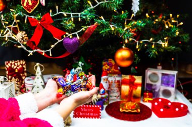 Noel ağacının önünde çikolatalı şekerlemeleri tutarken. Noel ağacı süslemek ya da hediyeleri açmak. Bükreş, Romanya, 2020