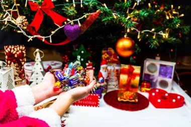 Noel ağacının önünde çikolatalı şekerlemeleri tutarken. Noel ağacı süslemek ya da hediyeleri açmak. Bükreş, Romanya, 2020