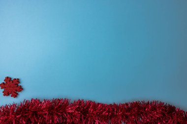 Kırmızı parlak kar tanesi süslemeli ve kırmızı çelenkli mavi Noel arkaplanı. Noel kompozisyonunu kopyalamak için üst görünüm.