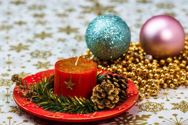Süslü yılbaşı kırmızı mumuna yakın bir yerde. Noel kompozisyonu, mevsimlik dekorasyonlar ve süsler, renkli Noel arkaplanı Noel havası konsepti.