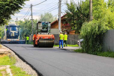 Bükreş, Romanya - CIRCA 2022: İşçiler ve asfaltlama makineleri. İnşaat, yeni yol asfaltlanıyor.