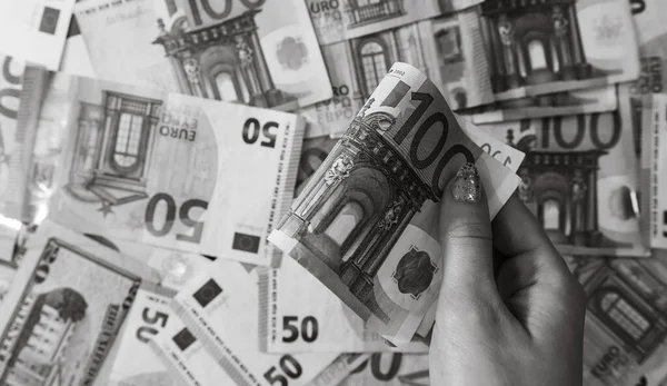 Hand giving money like bribe or tips isolated on banknotes background. EURO and USD currency banknotes close up. Reward for hard work, inflation, finance and business concept