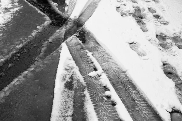 Car and foot tracks in the snow, snowy road.