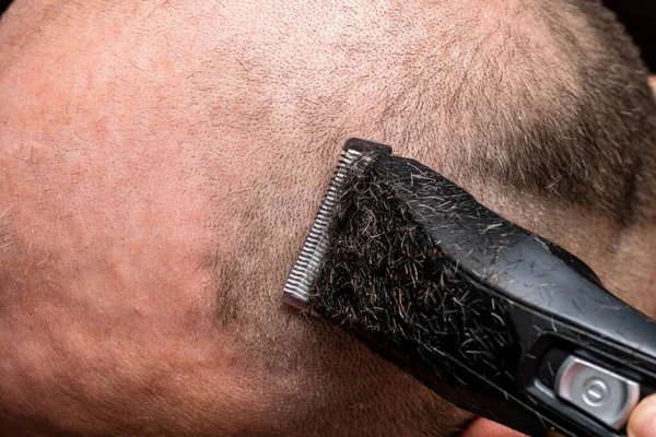 Man shaving or trimming his hair using a hair clipper