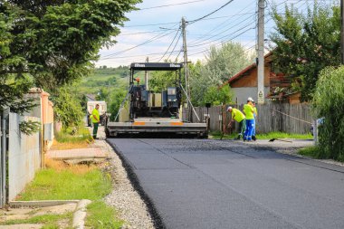 İşçiler ve asfaltlama makineleri. Romanya 'nın Bükreş kentinde inşaat ve yeni karayolunun asfaltlanması, 2022