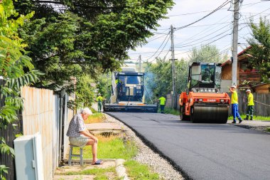İşçiler ve asfaltlama makineleri. Romanya 'nın Bükreş kentinde inşaat ve yeni karayolunun asfaltlanması, 2022