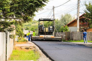 İşçiler ve asfaltlama makineleri. Romanya 'nın Bükreş kentinde inşaat ve yeni karayolunun asfaltlanması, 2022