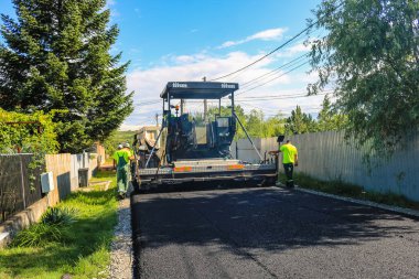 İşçiler ve asfaltlama makineleri. Romanya 'nın Bükreş kentinde inşaat ve yeni karayolunun asfaltlanması, 2022