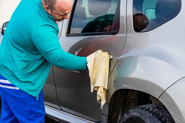 Man polishes car, using microfiber cloth. Romania, Bucharest, 2022