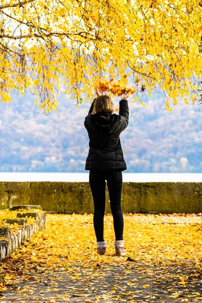 Autumn leaves fallen on alone woman walking on the autumn alley