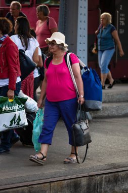 Tourist pulling luggage. Commuters walking at railroad station platform in Bucharest, Romania, 2022
