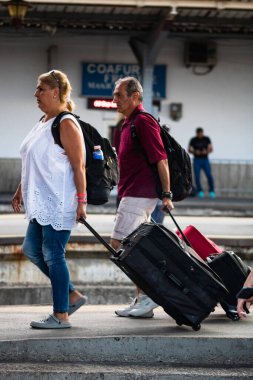 Tourist pulling luggage. Commuters walking at railroad station platform in Bucharest, Romania, 2022