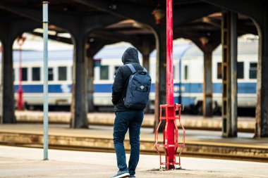 Tourist pulling luggage. Commuters walking at railroad station platform in Bucharest, Romania, 2022