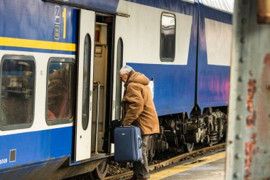 Tourist pulling luggage. Commuters walking at railroad station platform in Bucharest, Romania, 2022